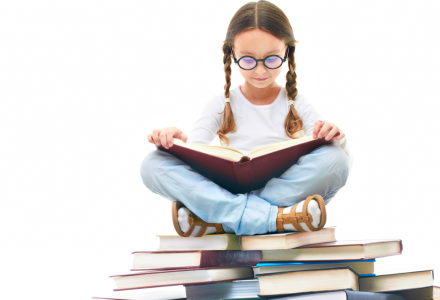 young girl with pigtails and glasses reading atop a pile of books