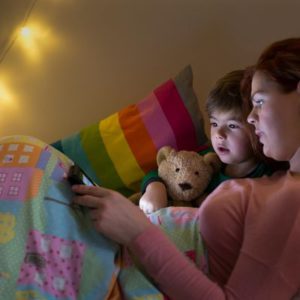 woman and boy reading on tablet in bed