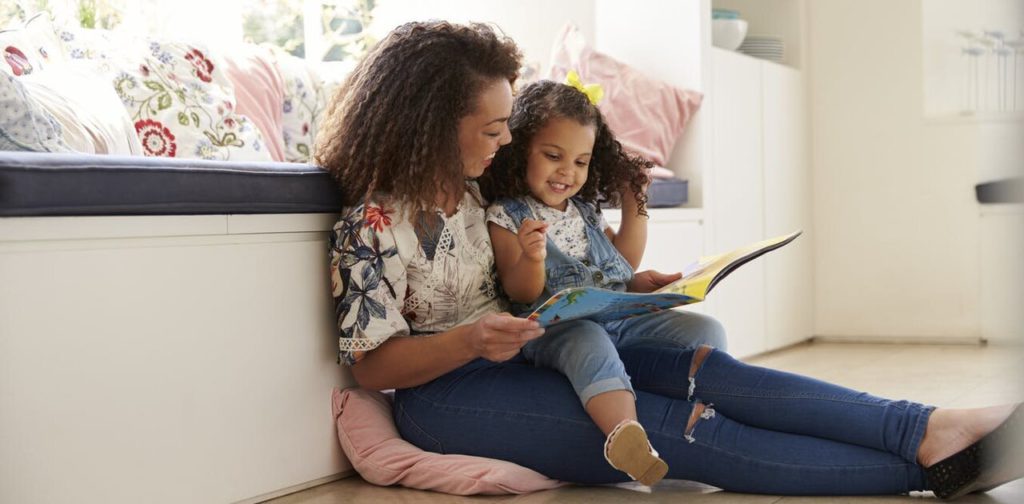 Parent and child reading a book together at home
