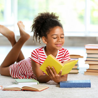Girl surrounded by books and reading a book