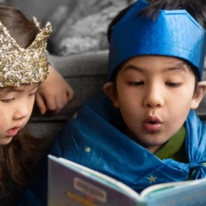 girl and boy in fancy dress reading a book together