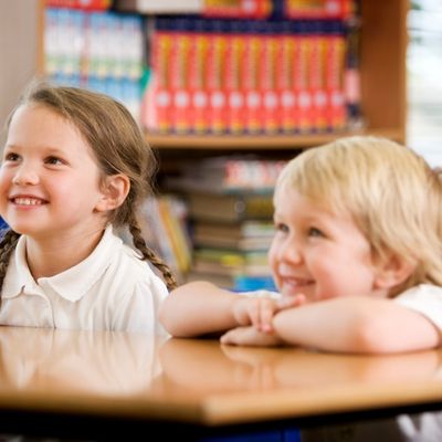Two children smiling at their desk in school